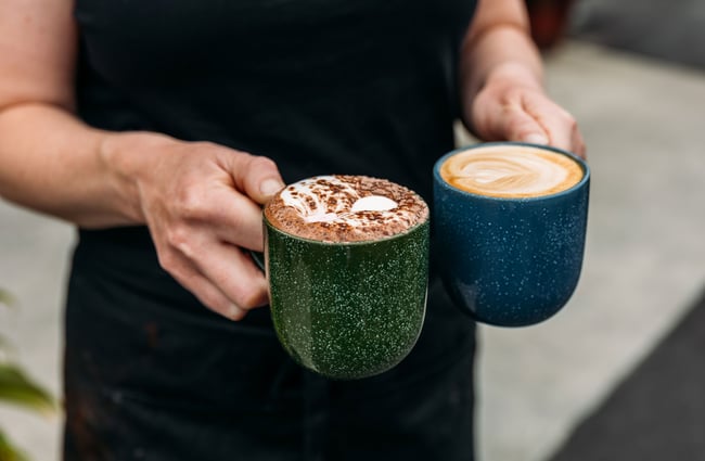 A close up of a person holding a coffee and a coffee.