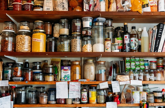 Seeds, spices and other ingredients in glass jars on wooden shelves.
