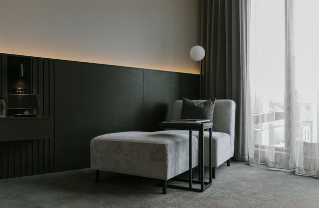 A lounge seat placed in the corner of a bedroom inside The Mayfair Christchurch.