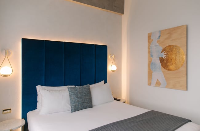 A white bed with blue bed head.