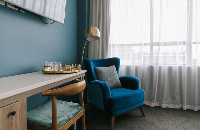 A blue arm chair in a hotel room.