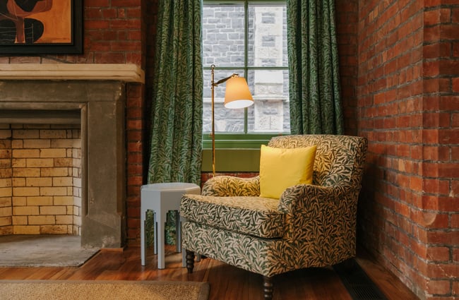 Patterned chair in corner of the room next to window.