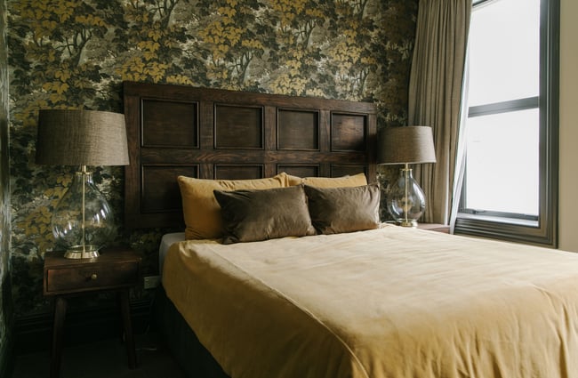 A bed dressed green and yellow in pillows and duvet cover inside The Old Confectionery Oamaru.