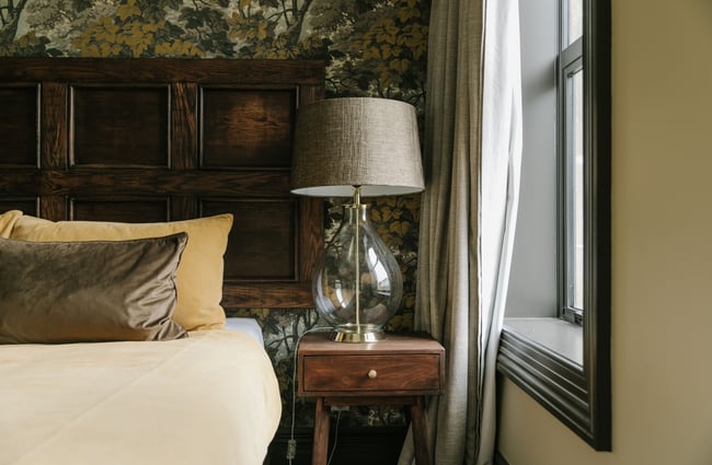 A close up of a lamp on a bedside table.