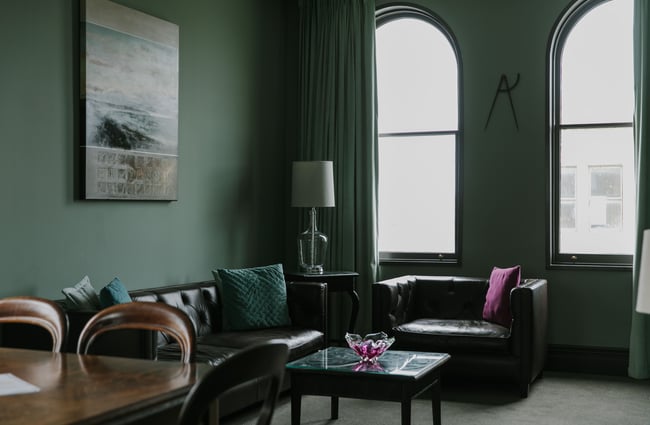 A leather couch and chair inside the living room at Old Confectionery Oamaru.