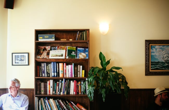 A man sitting next to a bookcase.