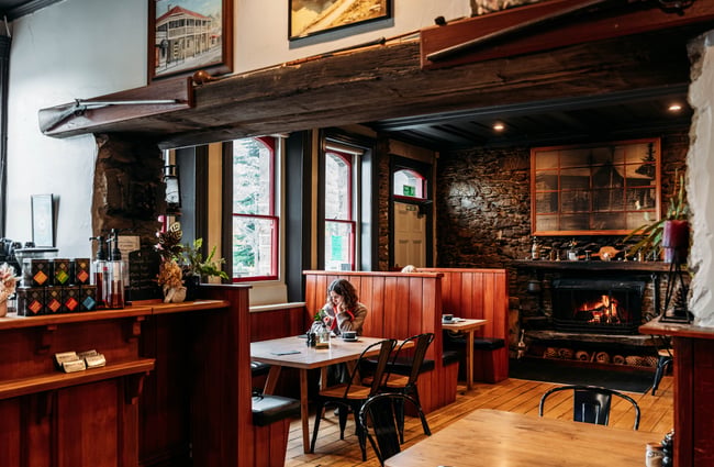 Customer sitting in a booth with the fire in the background at The Post Office Cafe and Bar.