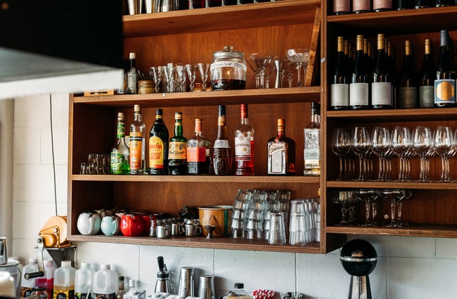 Bottles of liquor and glasses on shelves.