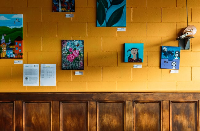 Small works of painted art on a painted wall.