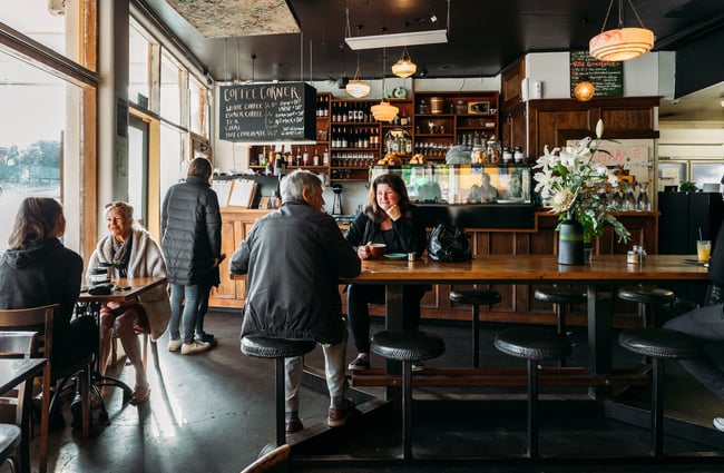 Customers sitting at tables inside a wooden decorated Raumati Social Club.