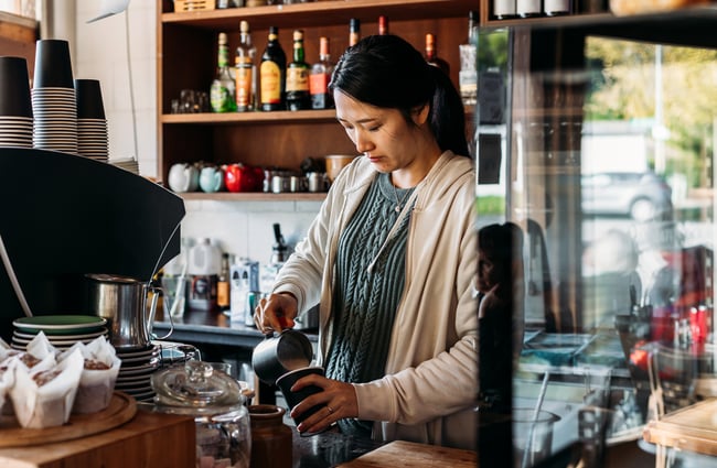 A barista making coffee behind a counter.