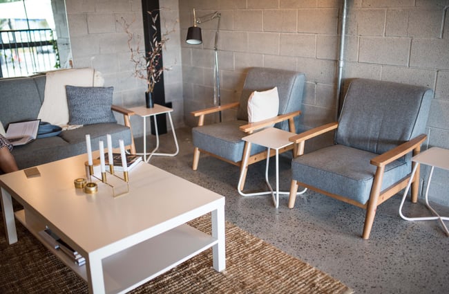Grey couches inside against a grey concrete wall.