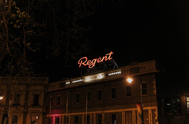Exterior of theatre with neon sign at the top of the building.
