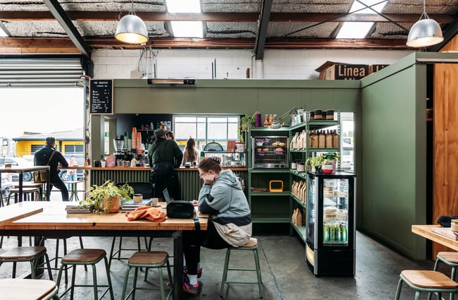 Customers waiting to order at the cafe counter and customers sitting at tables at The Roastery.