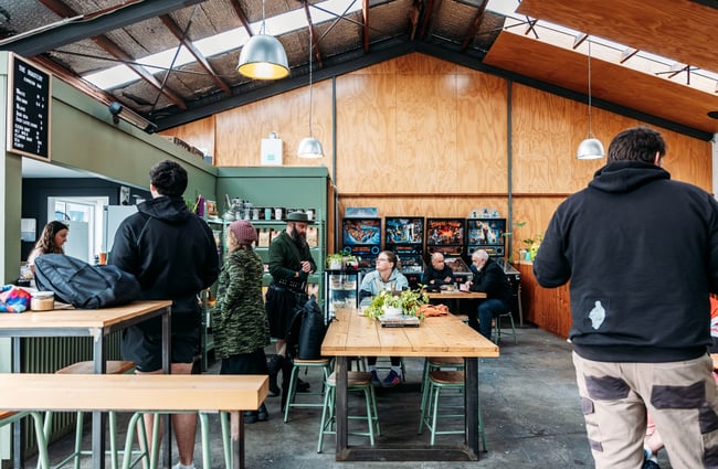 Customers waiting for their orders in the cafe space and customers sitting at tables at The Roastery.