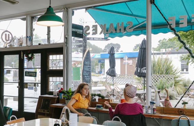 Two women chatting at the window seat inside The Running Duck Café in Geraldine.