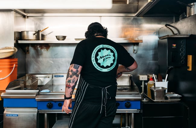 The back of a chef cooking in a kitchen.