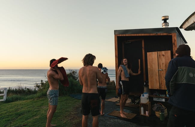 People standing around a portable sauna at dusk.
