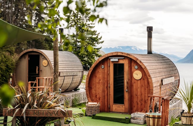 Two wooden saunas with the lake in the background at Secret Sauna.