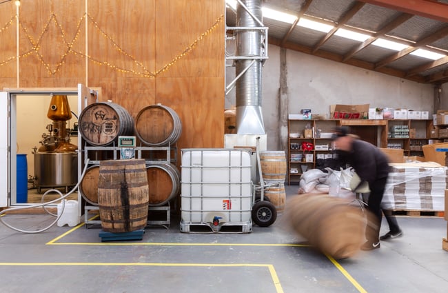Man rolling a barrel in the distillery at The Spirits Workshop.
