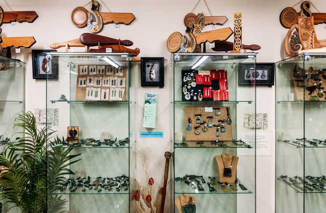 Jewellery and green stone works of art on display inside a gallery.