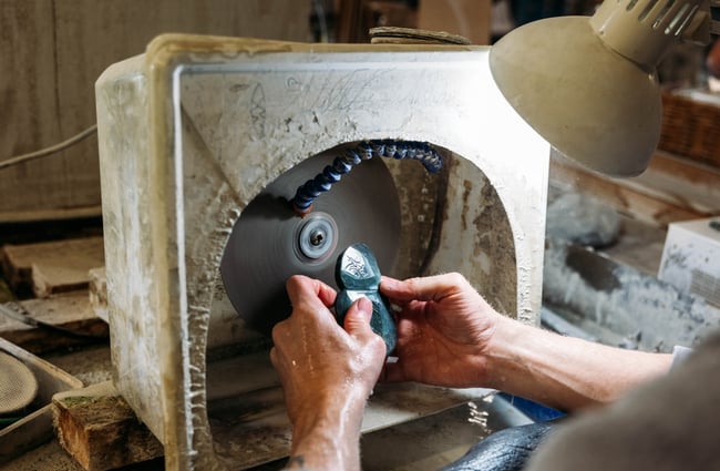 Hands carving green stone in a studio.