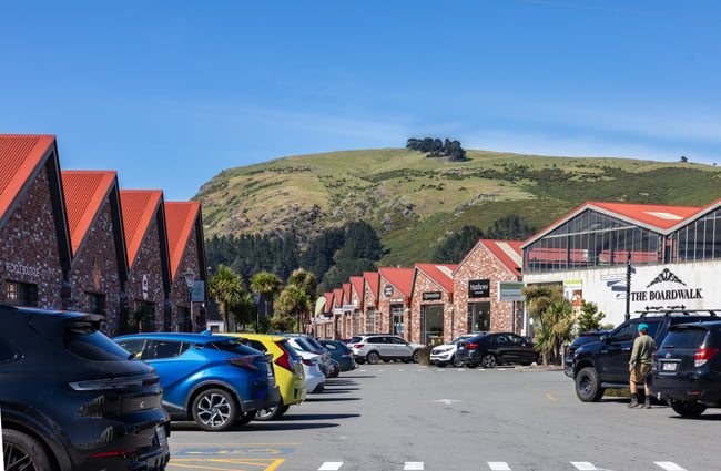 The outside of the red bricked buildings on a bright sunny day, with cars in the car park and a hill in the background at The Tannery.