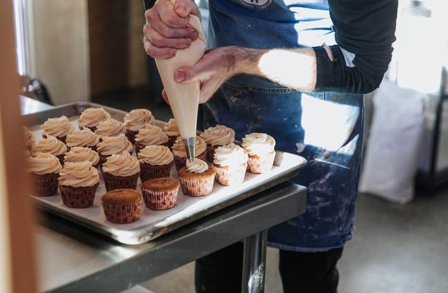 Icing being piped onto cupcakes.