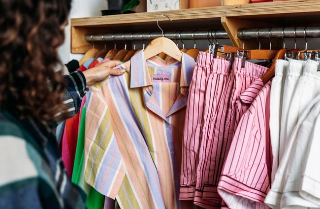 Close up of customer pulling Mosey Me pyjamas from rack at boutique store