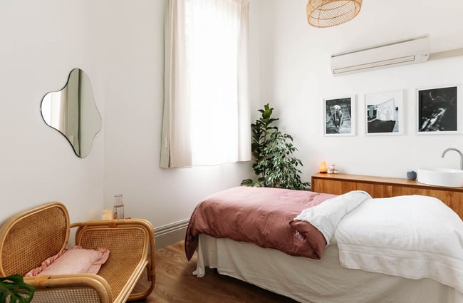 Modern and serene beauty salon room with bed, plants and a rattan chair in the corner