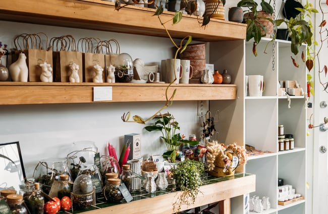 Flowers and candles on display on white shelves inside The Wilderness.