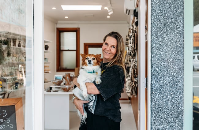 Shop owner holding her dog in the doorway of The Wobbly Pot.