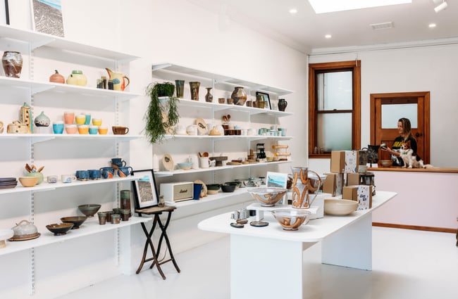 Bright white shop interior of The Wobbly Pot with colourful products on the shelves and display tables.
