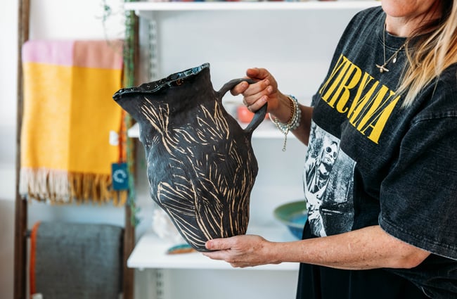 Shop owner holds a vase at The Wobbly Pot.