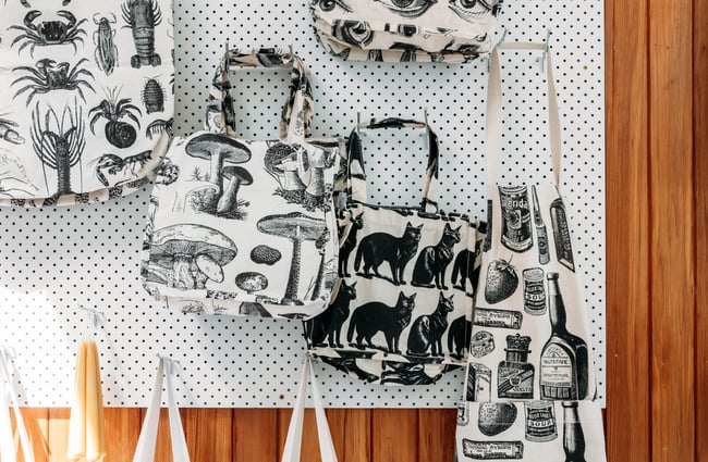 Printed tote bags hanging up on the wall at The Wobbly Pot.