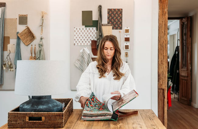 A staff member flicking through a fabric samples book at a wooden table at The Workroom.
