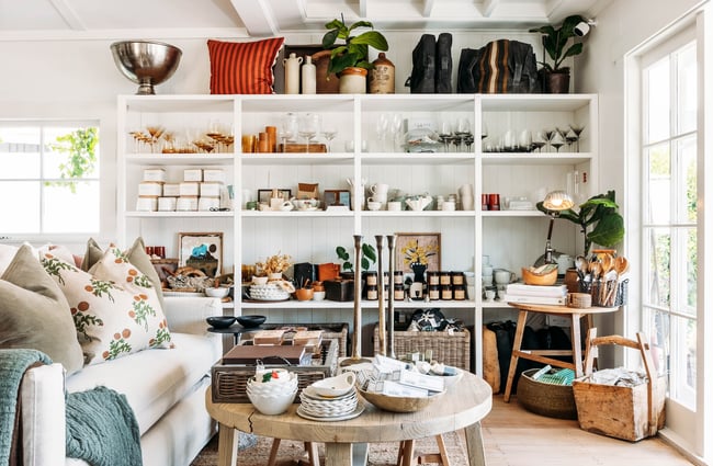 White shelves of crockery, glassware and other homewares on display in a sunlight-filled room in The Workroom.
