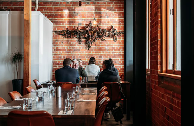 People sitting at tables chatting inside a restaurant.