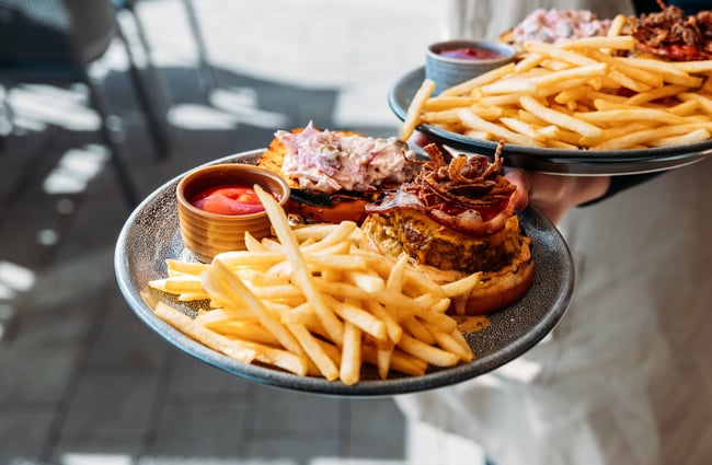 A close up of burgers and chips on plates.