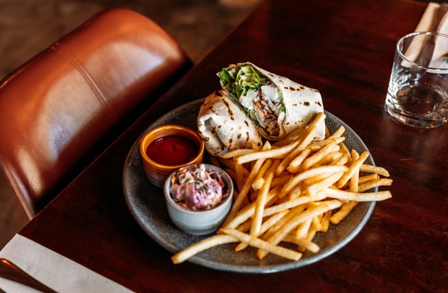 A burrito and fries platted on a table.