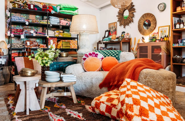 A low couch decorated with bright coloured cushions and blankets.
