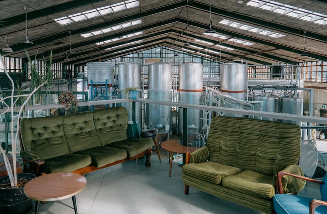 Couches on mezzanine floor in front of big beer tanks.