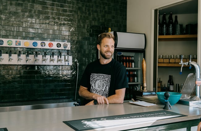 Brewer smiling at bar area at Three Boys Brewery in Christchurch.