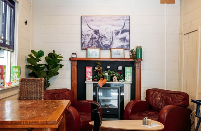 Two comfy chairs and a fireplace inside Three High Street cafe in Rangitikei.