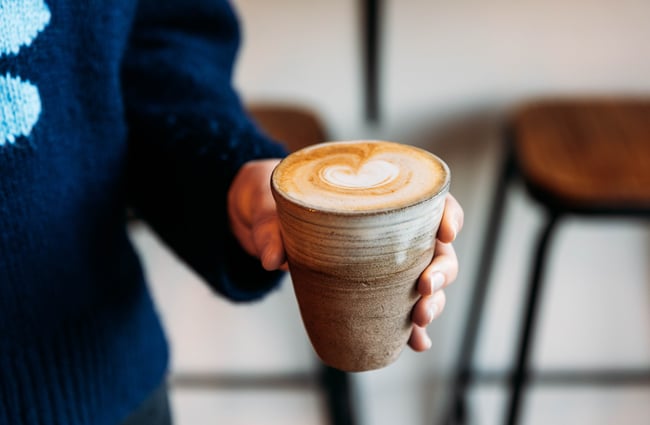 A hand holding a coffee.