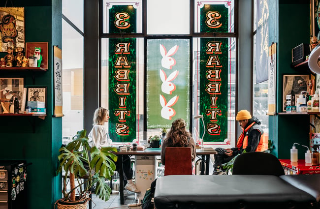 People sitting at a table inside Three Rabbits Tattoo.