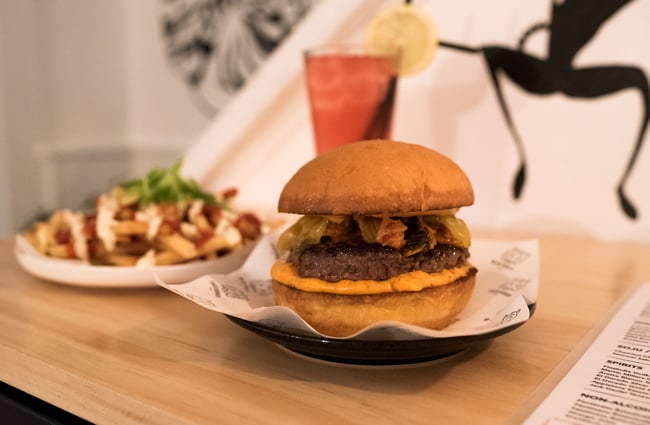 Burger, fries and a drink on a wooden table.