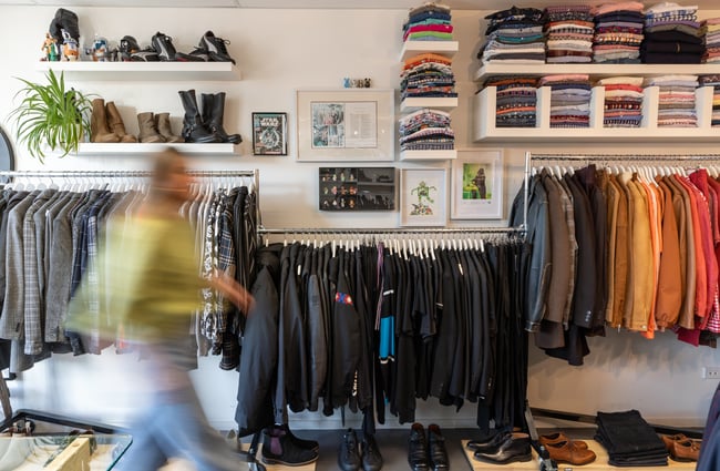 Clothing on racks and customer walking by at To Be Continued.