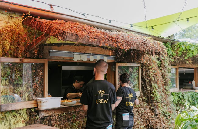 Two crew members standing by kitchen hatch.