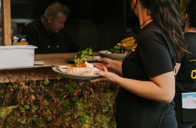 Woman holding a plate of food from Toad Hall, Motueka.